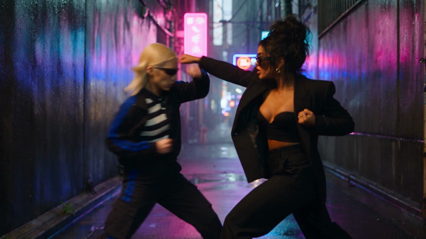 Xstacey Blade facing Suzy in the neon-lit alley
